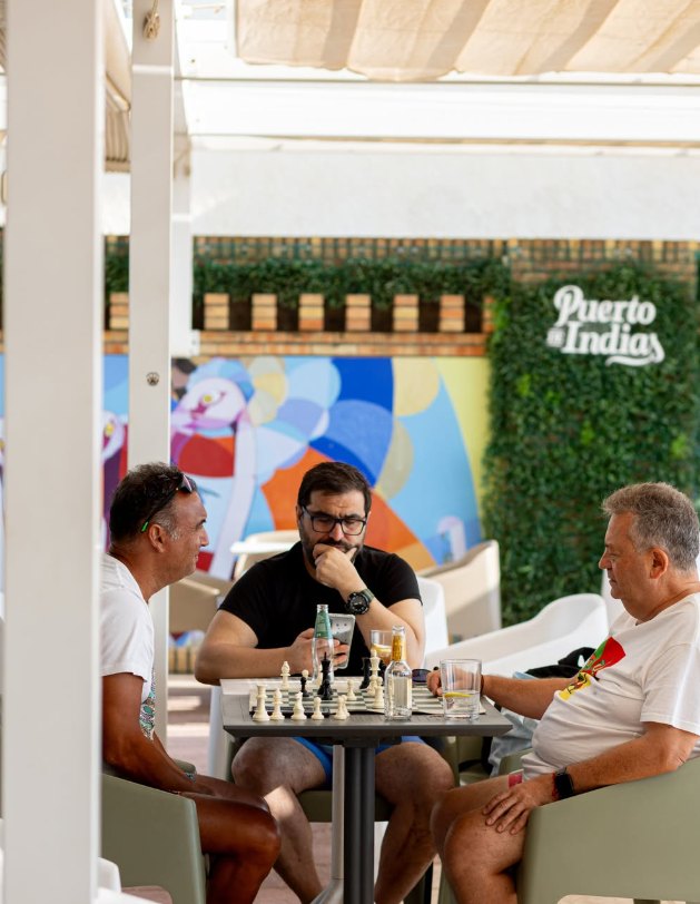 Tres amigos jugando al ajedrez en la terraza de La Playa Chipiona