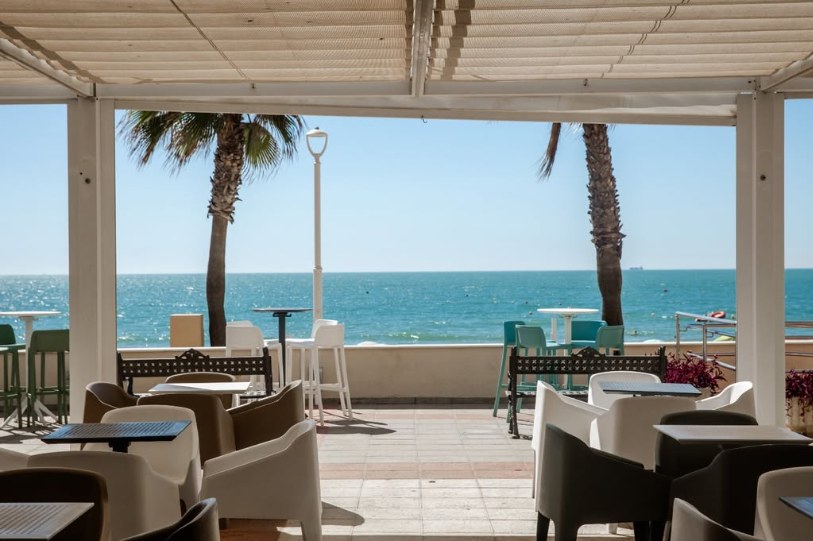Terraza de La Playa Chipiona con palmeras y el mar